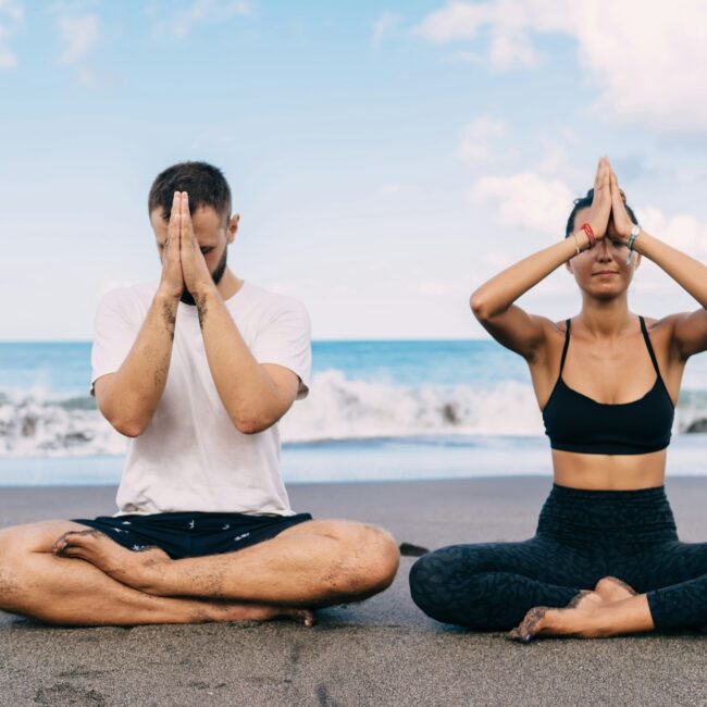 Athletic friends breathing and feeling harmony mindfulness in asana near ocean