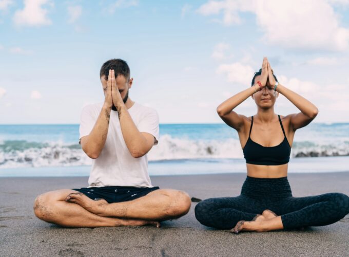 Athletic friends breathing and feeling harmony mindfulness in asana near ocean